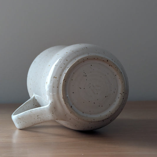 Speckled ceramic mug on a wooden surface with a gray background