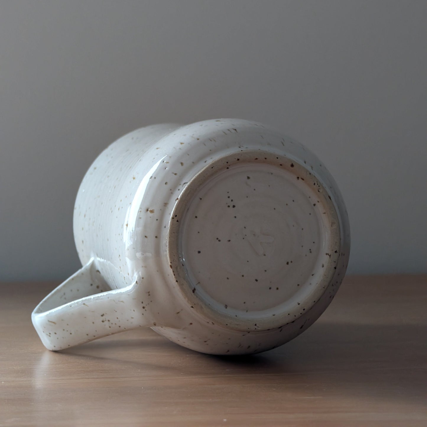 Speckled ceramic mug on a wooden surface with a gray background