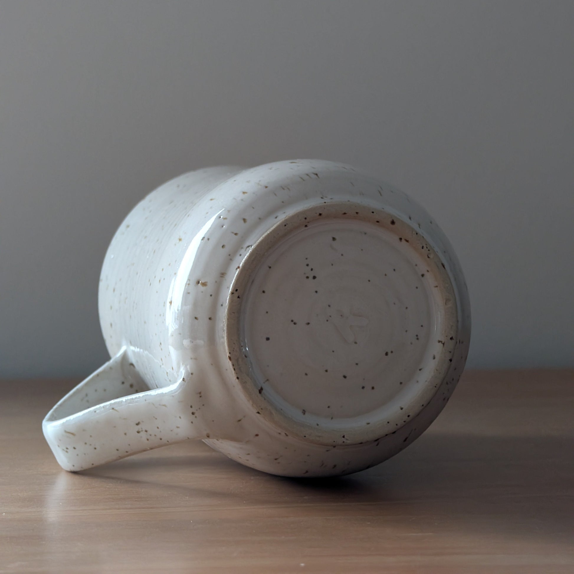 Speckled ceramic mug on a wooden surface with a gray background