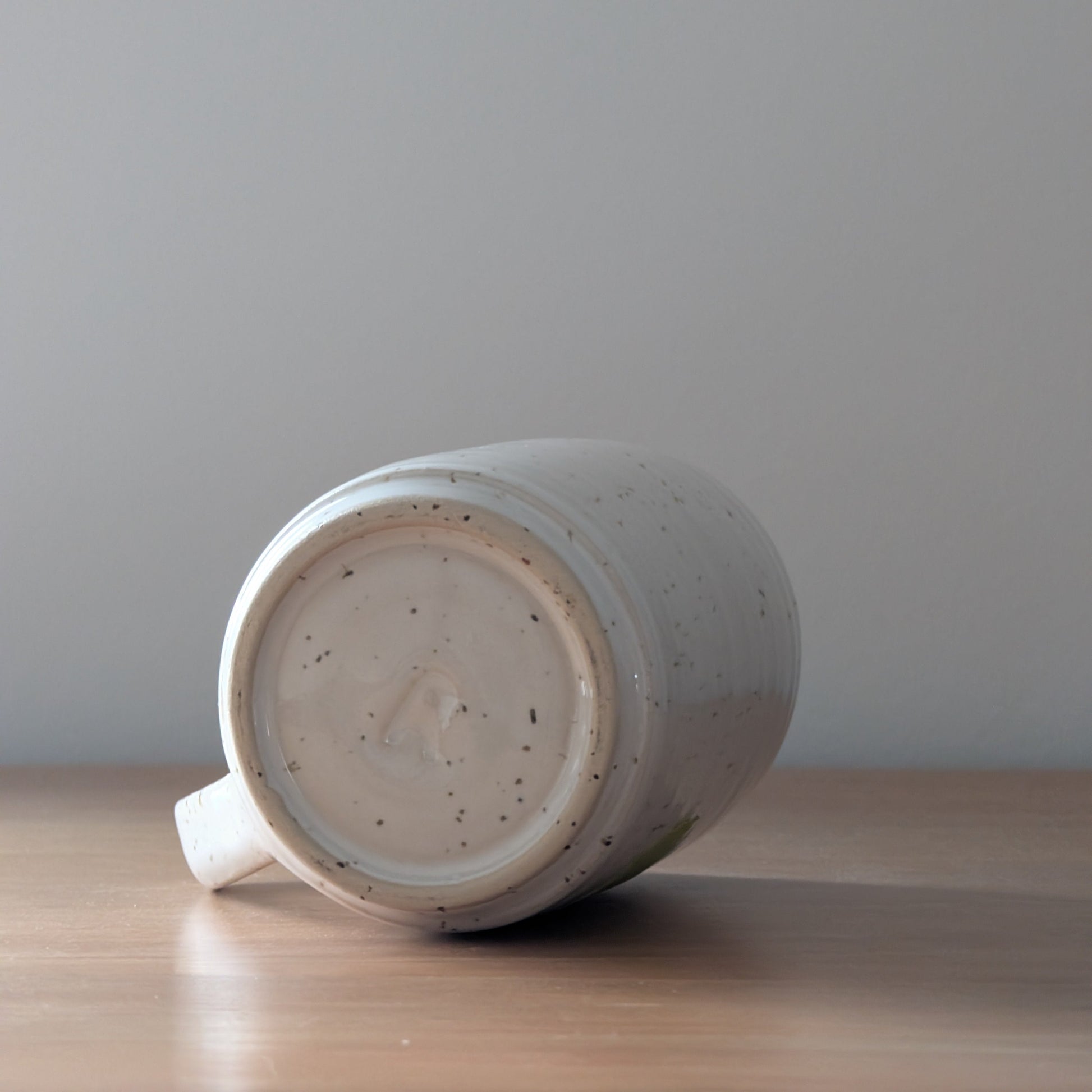 White ceramic mug on a wooden surface with a gray background
